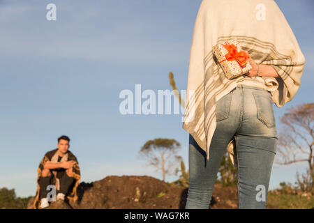 Hispanic man and woman échanger des cadeaux sur les rochers un après-midi d'automne avec beaucoup de soleil Banque D'Images