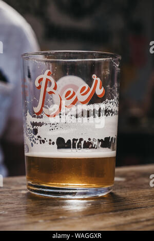 Close up of a presque vide verre de bière avec une "bière" moderne écrit, sur une table en bois, selective focus. Banque D'Images