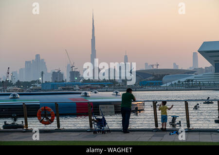 Père et regarder le coucher de soleil sur le centre-ville de Dubaï avec Burj Khalifa dans le centre. Vue depuis Dubai Festival City. Banque D'Images