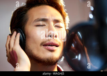 Young Asian Woman enjoying chantant une chanson en studio d'enregistrement moderne Banque D'Images