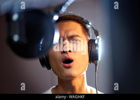 Young Asian Woman enjoying chantant une chanson en studio d'enregistrement moderne Banque D'Images