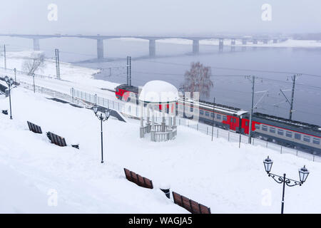 Paysage de neige d'hiver avec train électrique le long de la rivière avec une rotonde et pont vintage automobile dans l'arrière-plan Banque D'Images