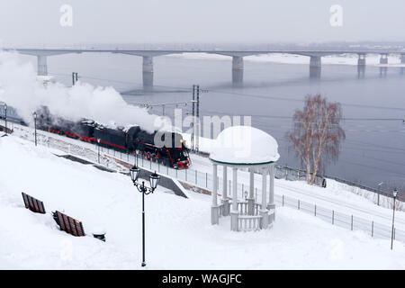 Paysage de neige d'hiver avec locomotive à vapeur se déplaçant le long de la rivière avec une rotonde et pont vintage automobile dans l'arrière-plan Banque D'Images