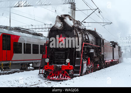 Locomotive à vapeur et électriques modernes-unité à proximité de la station de train se tenir en hiver Banque D'Images