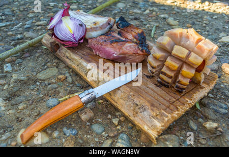 La viande de boeuf avec du bacon et l'oignon rouge sur une planche à découper. Une table à partir d'anciennes cartes, style rural. Nourriture traditionnelle, aliment sain,l'alimentation biologique. Banque D'Images