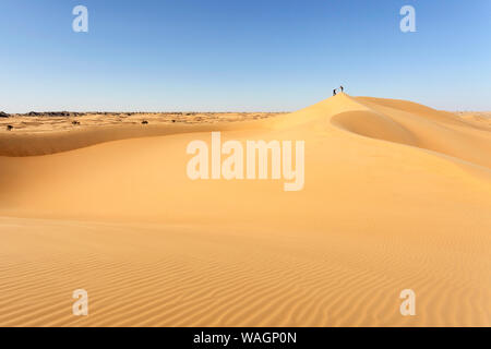 Deux homme s'aider mutuellement à grimper sur les dunes du désert dans la cannelle, Entre désert et Mahout Duqm, Oman Banque D'Images