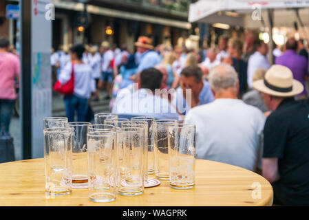 Verres de bière vides sur la table en bois à côté de walking street, et d'arrière-plan flou de personnes debout, assis, sortir et boire de la bière sur l'extérieur. Banque D'Images