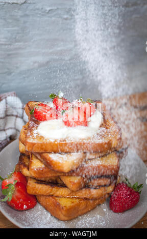 Du pain perdu aux fraises, noix de coco lambeaux, miel et sucre en poudre, sur fond de bois Banque D'Images