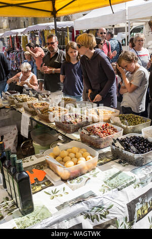 Les clients jusqu'à la ligne d'un décrochage olives acheter au marché de plein air hebdomadaire à Plougasnou, France Banque D'Images