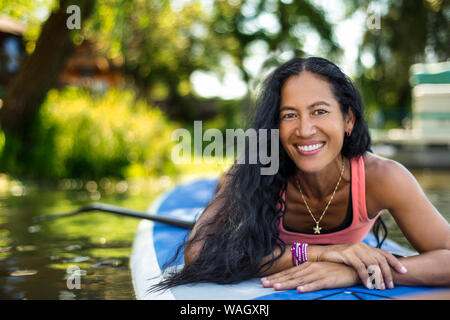 Mid adult woman se prépare pour paddleboarding. Banque D'Images