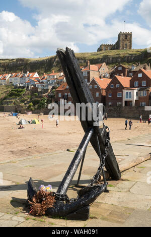 Une vieille ancre avec un stock de bois sur Tate Hill pier avec l'église St Mary à l'arrière-plan, Whitby, North Yorkshire, England, UK Banque D'Images