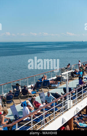 Les passagers à prendre le soleil sur la terrasse de la piscine d'un navire de croisière Banque D'Images