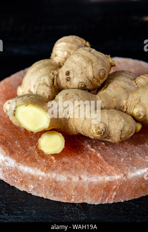 Les racines de gingembre frais sel rose de Perse sur board close up sur fond de bois noir, concept alimentaire asiatique Banque D'Images