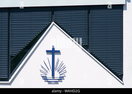 Les stores abaissés sur une église moderne et récemment construit avec une croix symbole avec rayons. Banque D'Images