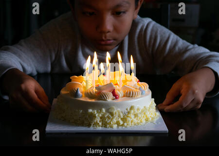 Un garçon avec un gâteau d'anniversaire avec des bougies. Banque D'Images