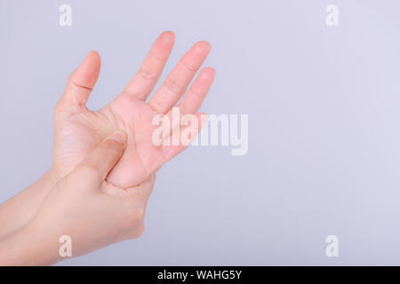 Femme souffrant de douleur à la main sur fond gris. Banque D'Images