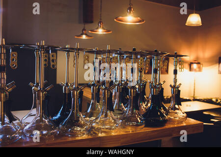 Groupe de pays d'hookahs avec tuyaux noirs sur la table dans le café. Fumer Shisha concept. Banque D'Images