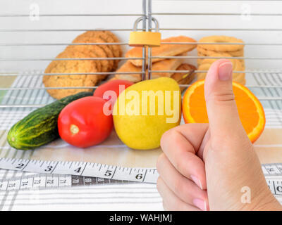 Main femme tient le pouce vers le haut. Les témoins sont dans la cage avec un cadenas verrouillé. La saine alimentation et de l'interdiction de junk food concept. Banque D'Images