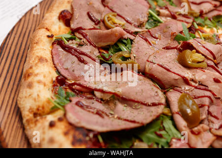 Pizza au rôti de bœuf, salade de roquette, Jalapeno piment et sauce barbecue Banque D'Images