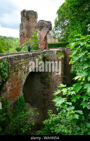 Un homme traverse un grand pont voûté en brique et pierre menant aux ruines de Roslin (Château) Rosslyn au-delà des fragments visibles de la porterie, mete Banque D'Images