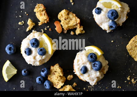 Trois bleuets citron cupcakes céto sur surface sombre avec la pâte de noix et d'amande charlottes et de fruits. Haut de la vue, télévision lay. Banque D'Images
