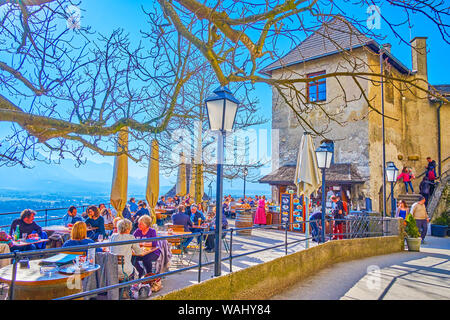 Salzbourg, Autriche - 27 février 2019 : La foule terrasse ensoleillée de Château de Hohensalzburg avec de petites tables et chaises de restaurant en plein air, sur Februa Banque D'Images
