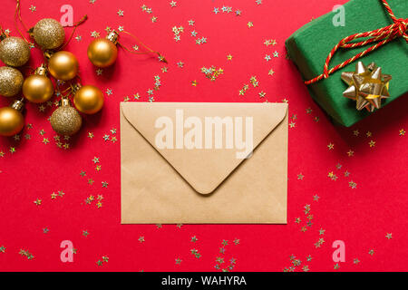Composition de Noël. Enveloppe, cadeau enveloppé sur fond rouge