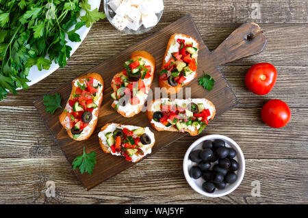 Bruschettas délicieux avec le fromage de chèvre et les légumes frais. Tranches de baguette croustillante à la feta, tomates, concombres, poivrons, olives, fines herbes. Br sain Banque D'Images