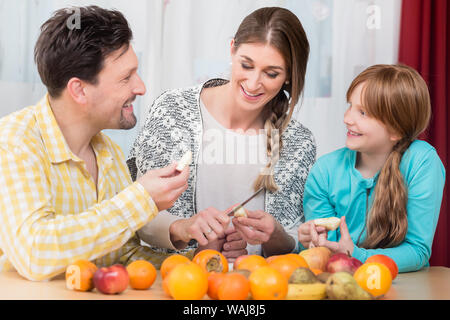 Woman cutting fruits sains pour son mari et sa fille Banque D'Images