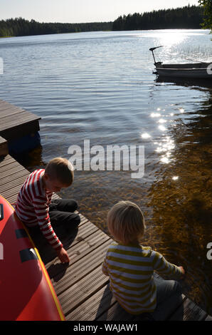 Deux petits garçons blonds, les frères jouant sur le lac, jetée par Sarkjarvi la Finlande. Banque D'Images