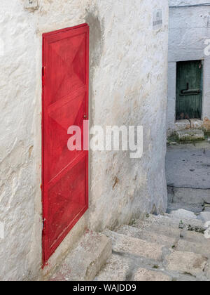 Ruelle avec une porte rouge et une porte verte dans la vieille ville d'Ostuni. Banque D'Images