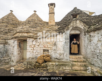 L'Italie, l'Alberobello. Femme en vêtements traditionnels en porte. Banque D'Images