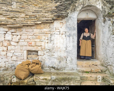 L'Italie, l'Alberobello. Femme en vêtements traditionnels en porte. Banque D'Images