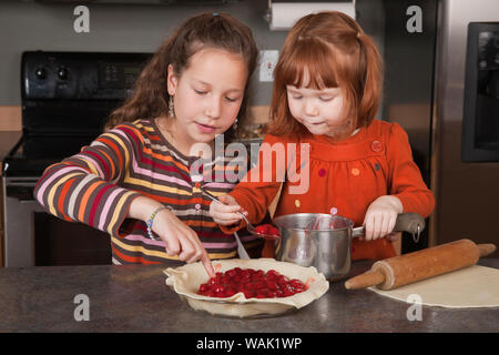 L'ajout de sœurs cherry pie du remplissage de tarte. (MR, communication) Banque D'Images