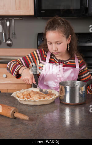 Girl ajout d'apple pie de remplissage à tarte. (MR, communication) Banque D'Images