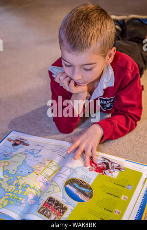 Sept ans la lecture de son atlas du monde livre. (MR) Banque D'Images