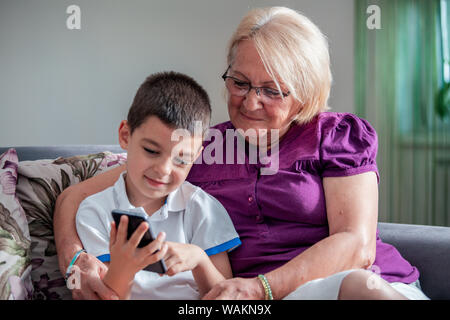 Grand-mère heureuse et mignon petit-fils using cellphone, portrait plus grand-mère des enfants et la fille s'amusant en tenant le téléphone en selfies, cheerful granny Banque D'Images