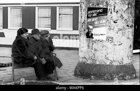 01 janvier 1990, Berlin, Potsdam : c'est l'élection à la Chambre du peuple qui est de préparer la réunification. Lothar de Maizière fait campagne pour l'Alliance démocratique à Potsdam. Trois des auditeurs en face de l'affiche : -la richesse pour tous, nous sommes un peuple, photo Lothar de Maizière. Meilleure qualité possible, de la date exacte de l'enregistrement non connue. Photo : Paul Glaser/dpa-Zentralbild/ZB Banque D'Images