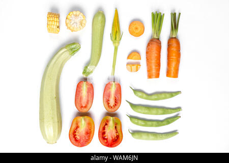 Mise en page créative faite de tomates, maïs, haricot, carotte, zucchinion fond blanc . Mise à plat, vue du dessus, copiez l'espace. Concept de saine alimentation. Banque D'Images