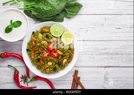 Biryani Panir aux épinards et au fond en bois blanc Raita avec décor. Panir aux épinards Biryani est végétarienne La cuisine indienne plat d'épinards, paneer, bas Banque D'Images