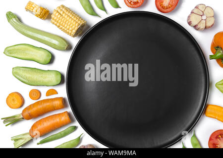 Mise en page créative faite de haricot, les tomates, le poivron, la carotte, l'ail, le maïs, la courgette, l'oignon et la plaque noire. Fond d'aliments biologiques. Mise à plat, vue du dessus, Banque D'Images