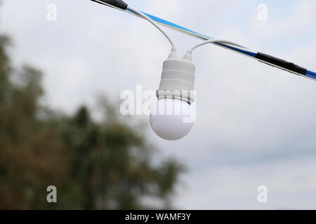 Ampoule ronde avec un ciel en toile de fond. Lampe blanche avec arrière-plan flou. Banque D'Images