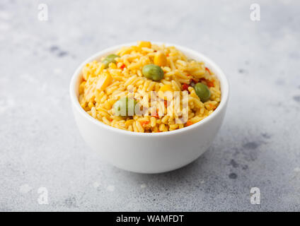 Bol blanc avec des légumes bio riz basmati sur fond clair. Le maïs jaune et les pois verts de paprika tranches. Banque D'Images