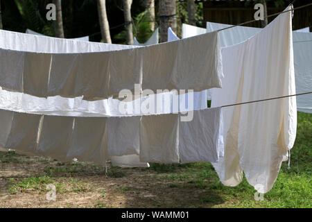 Le tissu blanc est exposé au soleil sur la corde à linge. Un grand drap blanc suspendu à une corde à linge. Banque D'Images