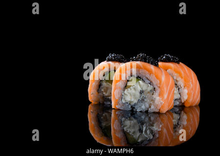 Sushi roll Philadelphia avec le saumon, l'anguille fumée, avocat, fromage à la crème sur fond noir. La nourriture japonaise Banque D'Images