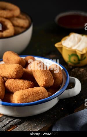 Quelques croquettes espagnoles dans une plaque d'émail blanc et bleu sur une table et quelques calamares a la romana, Fried squid battues typique de l'Espagne, anneaux en th Banque D'Images