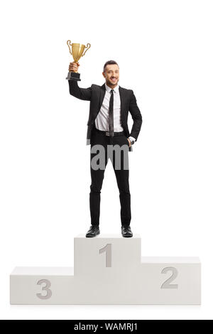 Portrait d'un homme en costume qui pose sur un piédestal avec un trophée Golden cup le premier endroit isolé sur fond blanc Banque D'Images