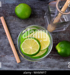 Vue de dessus les citrons et les tranches de lime pour detox de l'eau sur fond de bois gris, un pour l'eau potable saine alimentation et soins de la peau Banque D'Images