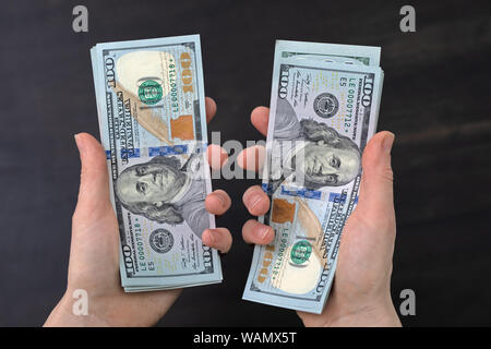 Dollars avec le visage de Benjamin Franklin dans le palms vous regarder. deux piles de dollars américains sur les mains Banque D'Images