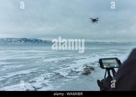 Sur l'épaulement tourné de caucasien homme battant quadcopter gelés sur le lac de l'Utah, USA Banque D'Images